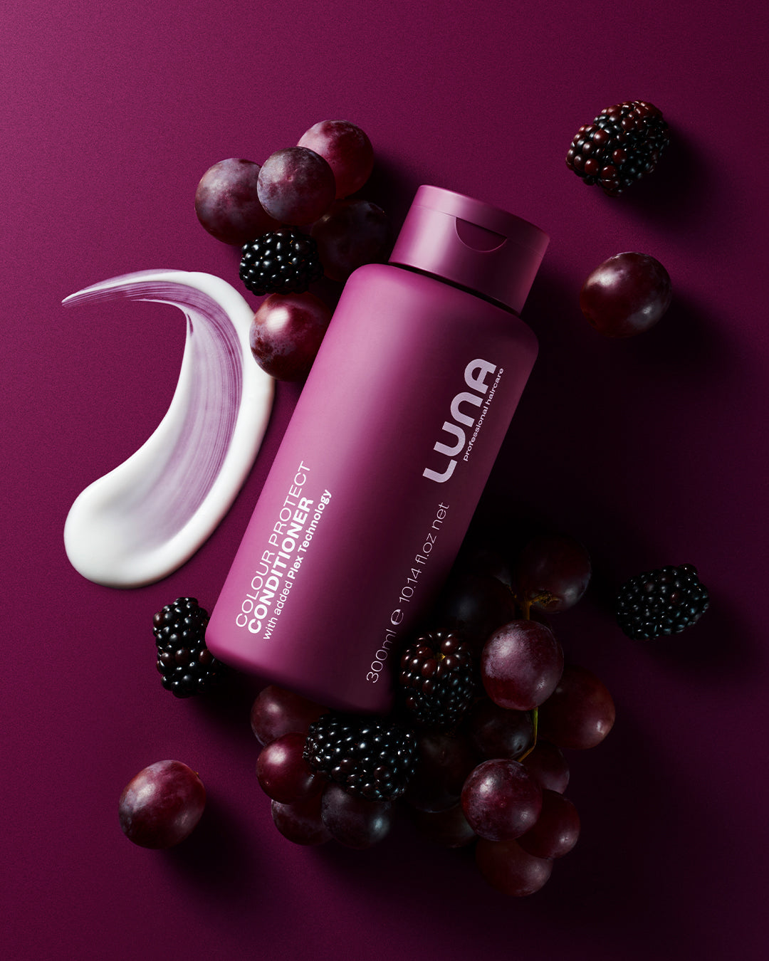 Luna hair care product bottle with grapes and blackberries on a purple background